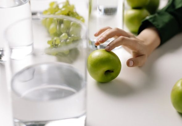 Refreshing image of green apples and grapes with glasses of water on a table, promoting healthy living.